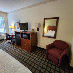 um quarto de hotel com uma cama, uma televisão e uma cadeira em Baymont by Wyndham Mackinaw City em Mackinaw City