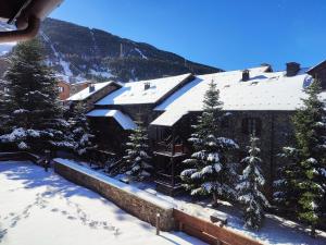a building covered in snow with trees and mountains at AC Apartaments Tarter Chalet in El Tarter