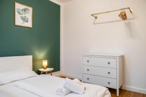 Un dormitorio con una cama blanca y una pared verde. en Neubau Wohnung am Eversten Holz, en Oldenburg