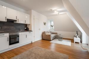 Una cocina con gabinetes blancos y una sala de estar. en Neubau Wohnung am Eversten Holz, en Oldenburg