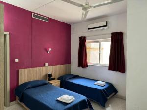 2 Betten in einem Zimmer mit lila Wänden in der Unterkunft Roma Hotel in Sliema