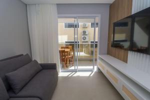 a living room with a couch and a large television at Nassau 203 - Excelente apartamento - Finamente mobiliado e decorado - À poucos metros da praia - (Consultar serviços de roupa de cama e banho) in Bombinhas
