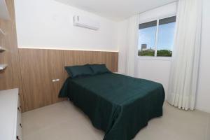 a bedroom with a green bed with a window at Nassau 203 - Excelente apartamento - Finamente mobiliado e decorado - À poucos metros da praia - (Consultar serviços de roupa de cama e banho) in Bombinhas +35 photos