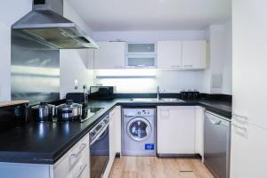 a kitchen with white cabinets and a washing machine at Canary Wharf-Stylish Flat-Fibre Wi-fi-10% discount in London