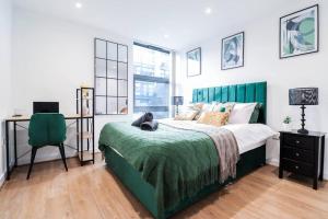 a bedroom with a bed with a green blanket and a desk at Canary Wharf-Stylish Flat-Fibre Wi-fi-10% discount in London