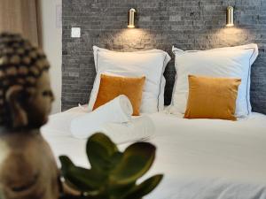 a bedroom with a bed with white sheets and orange pillows at Studio 26 - Parking - Climatisation in Aix-en-Provence