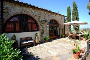a patio with a table and chairs and an umbrella at Tuopina Chianti House in Lornano