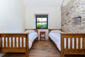 2 camas en una habitación con una pared de piedra en Bramble Cottage, hidden gem in Comber near Belfast en Ballygowan
