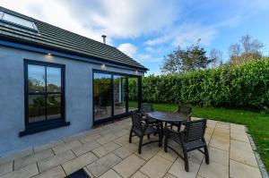 un patio con mesa y sillas. en Bramble Cottage, hidden gem in Comber near Belfast, en Ballygowan