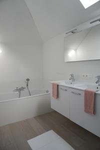een witte badkamer met 2 wastafels en een bad bij Casa Maris - Het huis van de zee - Viersterrenverblijf in Nieuwpoort