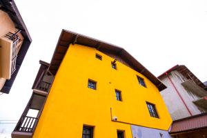 ein helles gelbes Gebäude mit einem schwarzen Balkon in der Unterkunft Casa Valentino in Buşteni