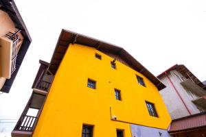 a bright yellow building with a black balcony at Casa Valentino in Buşteni