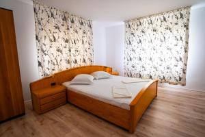 1 dormitorio con cama de madera y ventana en Casa Valentino, en Buşteni