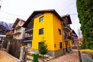 una casa amarilla con techo marrón en Casa Valentino en Buşteni