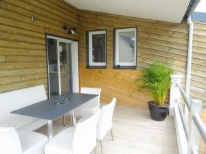 eine Terrasse mit einem Tisch und weißen Stühlen in der Unterkunft Abri Cotier in Hautot-sur-Mer