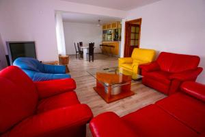 ein Wohnzimmer mit roten Sofas und gelben Stühlen in der Unterkunft Casa Valentino in Buşteni