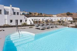 a large swimming pool with chairs and a building at Villas Scirocco in Fira