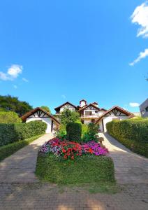 une maison avec des fleurs au milieu d'une allée dans l'établissement Chalés Leopoldo em Monte Verde, à Monte Verde