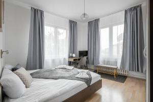 a bedroom with a bed and a desk and windows at Spacious 3BD Central apartment in Sofia