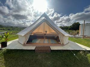 Maleka Farm: Tent Glamping North Shore Oahu في Laie: خيمة بيضاء مع سرير في حقل