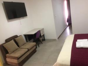 a room with a bed and a couch and a television at HOSTAL VERONA in Quito +24 photos