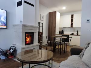 sala de estar con chimenea y mesa en Apartman Virgin Forest - FREE Garage Bjelašnica, en Bjelašnica