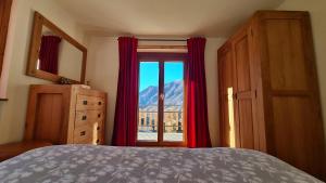 a bedroom with a bed and a window with red curtains at Chez Ferdinand in Valtournenche