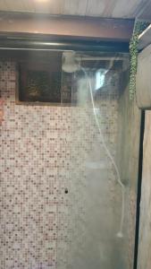 a shower with a hose attached to a tiled wall at Casa Rústica Lisboa 100m da praia in Balneário Camboriú