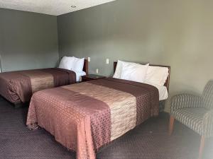 une chambre d'hôtel avec deux lits et une chaise dans l'établissement Hallmark Inn and Suites, à San Antonio