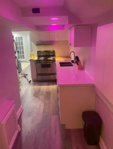 a pink kitchen with a stove and a sink at Cozy Basement Apartment in Brampton