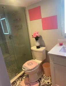 a bathroom with a toilet and a shower with a vase of flowers at Cozy Basement Apartment in Brampton