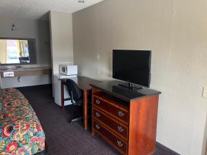 a hotel room with a bed and a desk with a television at Hallmark Inn and Suites in San Antonio