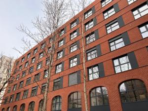 a red brick building with a tree in front of it at City Break Plac Wolności 6 Aparthotel in Poznań