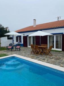 a house with a pool and chairs and an umbrella at Ferroa Guest House in Cano