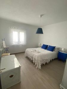 a white bedroom with a bed with blue pillows at Ferroa Guest House in Cano