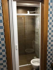 a bathroom with a toilet and a glass door at Residencial Recanto Ferrugem in Garopaba