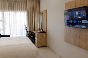 a hotel room with a bed and a flat screen tv at Acres Inn Klerksdorp in Klerksdorp