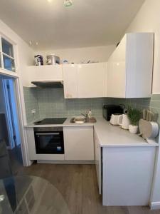 a kitchen with white cabinets and a sink at London's Charm - Best Spot in Modern 2BR, King's Cross in London