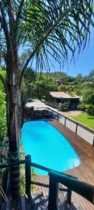 ein blauer Pool auf einer Terrasse mit einer Palme in der Unterkunft Residencial Recanto Ferrugem in Garopaba