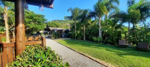 a walkway through a park with benches and palm trees at Residencial Recanto Ferrugem in Garopaba