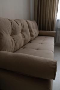 un sofá de cuero en una sala de estar con ventana en Евродвушка в ЖК Тениз en Kostanái