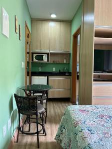 a room with a bed and a table and a kitchen at Piemonte Flat Hotel in Serra Negra