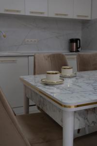 a kitchen with a marble table with two cups on it at Евродвушка в ЖК Тениз in Kostanay