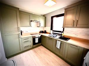 a small kitchen with green cabinets and a window at Grampian Serviced Apartments - Ladyhill Neuk - 1 Bedroom Apartment in Elgin