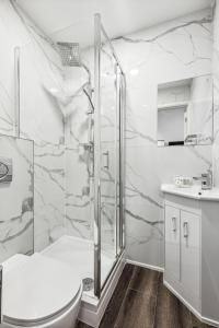 a white bathroom with a shower and a toilet at Sutherland Apartments in London