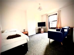 a bedroom with a bed and a chair and a television at Grampian Serviced Apartments - Ladyhill Neuk - 1 Bedroom Apartment in Elgin