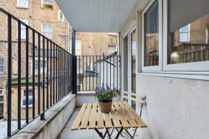 a wooden table on a balcony with a potted plant at Sutherland Apartments in London