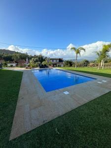 a large blue swimming pool in a grassy field at Casa Malheiro in Ponte de Lima