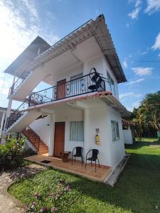 ein weißes Haus mit zwei Stühlen auf einer Veranda in der Unterkunft Hotel Mastranto in Villavicencio