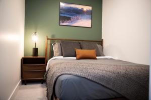 a bedroom with a bed with an orange pillow on it at Powder & Pines - Cozy 2 Bedroom with Hot Tub in Revelstoke